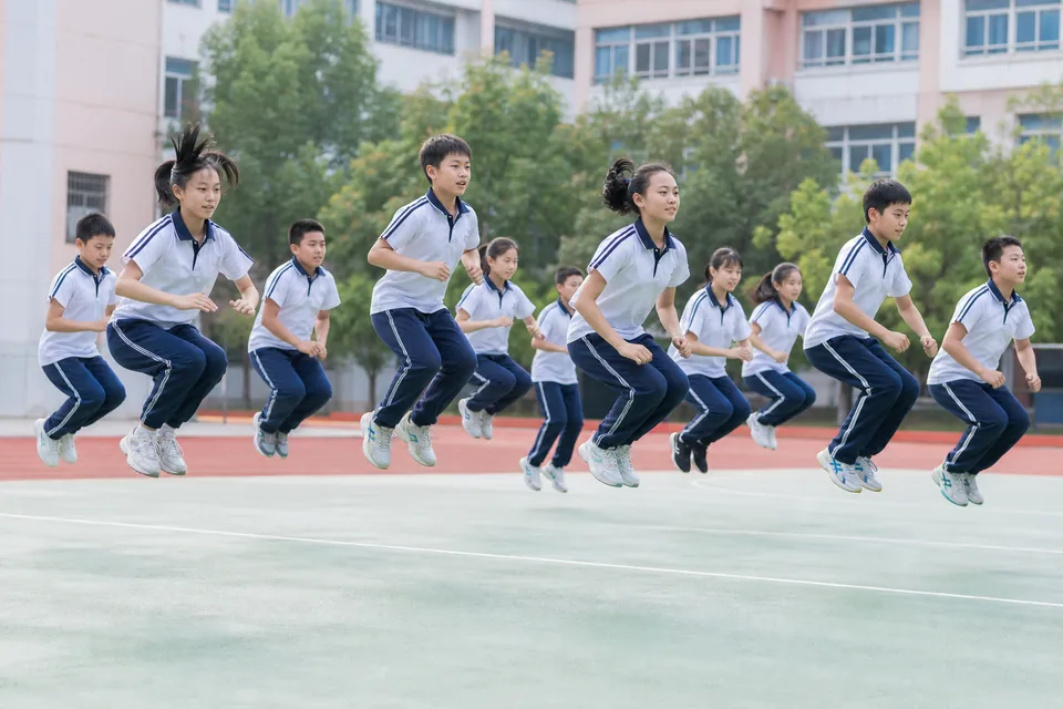 约十名学生在校园运动场同步进行蹲跳练习